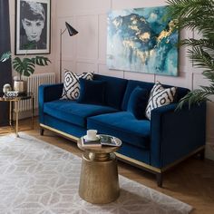 a living room with blue couches and paintings on the wall above them, along with a coffee table