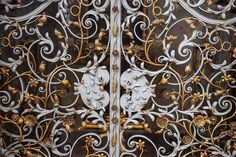 an ornate metal door with gold and white designs