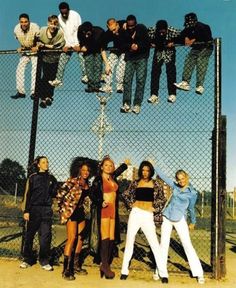 several people standing on top of a fence with their arms in the air and one person hanging from a chain link fence