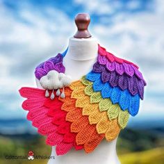 a white mannequin wearing a multicolored crocheted shawl with two birds on it