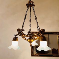 a chandelier with three lights hanging from it's sides in front of a mirror