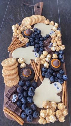 a platter filled with blueberries, crackers and other snacks on top of a wooden table