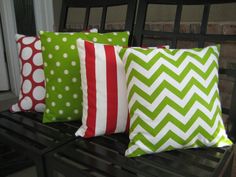 four green and white pillows sitting on top of a bench