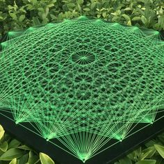 a green table with an intricate design on top of it in the middle of some bushes