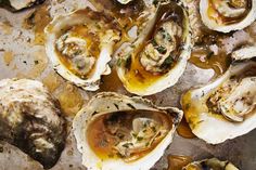 several oysters are sitting on a pan with sauce and seasoning sprinkles