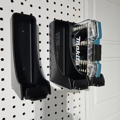 two black toothbrush holders mounted to the side of a white wall with holes in it