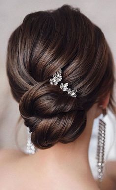 the back of a woman's head with hair combs in her hair and earrings