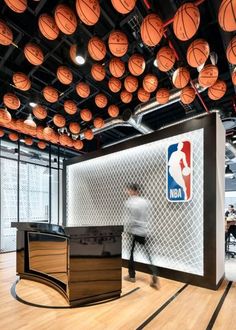 an office with basketballs hanging from the ceiling and a man walking in front of it