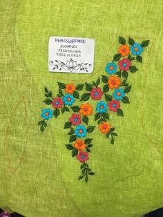 a green bag with flowers on it and a tag hanging from the back of it