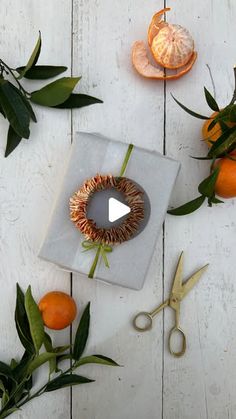 an arrangement of oranges, leaves and scissors on a white table