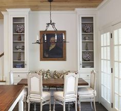 the dining room table is surrounded by white chairs and built - in bookcases