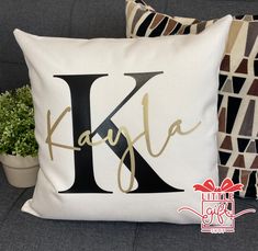 a pillow with the letter k on it and a potted plant next to it