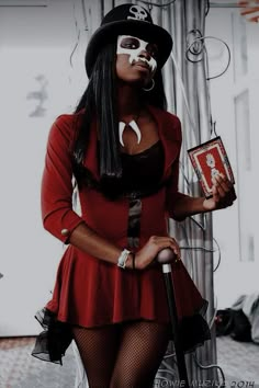 a woman in a red dress and black hat holding an umbrella with her face painted white