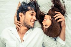 two people laying on top of each other with their hair blowing in the wind and smiling