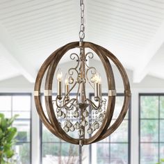 a chandelier hanging from the ceiling in a room with windows and potted plants