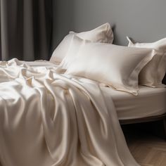 an unmade bed with white sheets and pillows