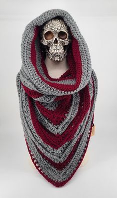 a crocheted skull wearing a red and gray scarf with a hood on it