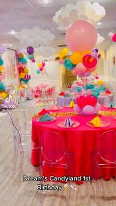 a room filled with balloons and tables covered in pink, yellow, and blue decorations