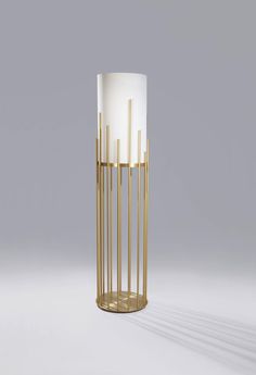 a tall gold and white lamp sitting on top of a table next to a gray wall