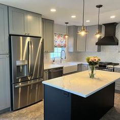 a kitchen with stainless steel appliances and marble counter tops, along with an island in the middle