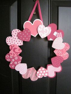 a valentine's day wreath hanging on the front door with pink and white hearts