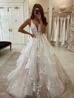 a woman taking a selfie while wearing a wedding dress with white flowers on it