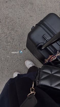 a black suitcase sitting on the ground next to a person's feet and handbag