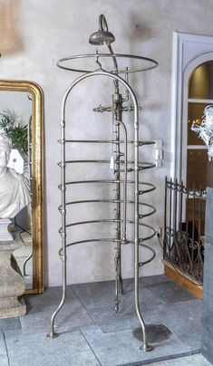 a tall metal rack with several glass bottles on it next to a mirror and statue