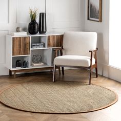 a white chair sitting on top of a wooden floor next to a shelf filled with vases