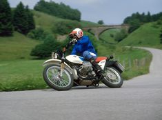 a man riding on the back of a motorcycle down a curvy road