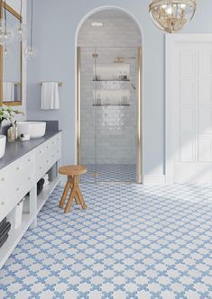 a bathroom with blue and white tiles on the floor, shower stall and sink area