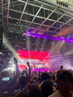 a large group of people at a concert with confetti falling from the ceiling