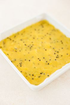 a square white dish filled with yellow food