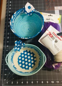 three bowls are sitting on a cutting board with yarn and scissors next to each other