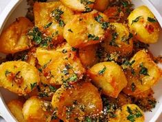 a white bowl filled with potatoes covered in herbs