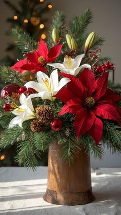 a wooden vase filled with red and white flowers on top of a table next to a christmas tree