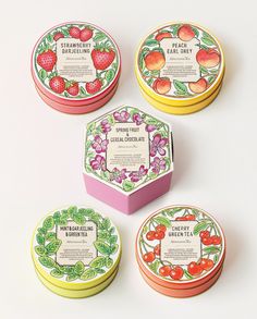 four round boxes with fruit designs on them