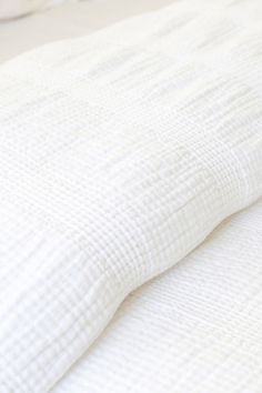 an unmade bed with white sheets and pillows