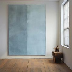 an empty room with a large blue painting on the wall and a small wooden bench