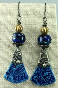 #1043, Striking Blue Silver Tinned Ceramic Charms by Sasha Crow are paired with Patricia Ritchie Glass Beads and Czech Glass Melon Beads. Dark Bead Caps & Black Niobium earwires finish off these earrings. The earrings are 2.3 long from the top of the earwire, 2 inches from the top of the earrings, and .5 inches wide. Each earring is a very light weight at .1 ounce. Please treat Chris Kaitlyn Jewelry like Wearable Art by putting them on after applying hair sprays, perfume, chemicals, soaps, water, etc. Packaging and Shipping to the United States is included in the price. "Chris Kaitlyn's Jewelry is fabulous. I buy my clothes to match the earrings that I purchase from Chris's creative collection!" Sage Vanzandt, Olympia, Washington. Read the About section to learn more about Chris Kaitlyn Je Handmade Artisan Blue Earrings, Artisan Handmade Blue Earrings, Artisan Blue Earrings, Blue Bohemian Earrings For Pierced Ears, Bohemian Teardrop Blue Earrings, Artisan Blue Drop Earrings, Artisan Blue Nickel-free Earrings, Adjustable Blue Bohemian Earrings, Blue Bohemian Dangle Earrings