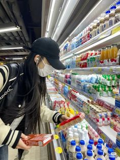 a woman wearing a face mask while shopping in a grocery store with food items on shelves