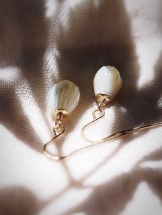 These simple gold pikake earrings exude Hawaii's natural beauty. These gold earrings feature hand carved mother of pearl pikake flowers reminiscent of Hawai'i's flower leis. They are perfect solo or teamed with our other earrings. ✦ DETAILS ✦✧ Name: Kamakana (KA ma KA na) - the gift.✧ 14kt Gold Filled w/carved mother of pearl shell Pikake flowers.✧ 1 inch drop length.✧ All Ke Aloha Jewelry pieces come packaged thoughtfully, beautifully, and ready for gift giving. Handmade Gold Petal-shaped Jewelry, Mother Of Pearl Single Earring For Gift, Delicate Mother Of Pearl Drop Earrings, Mother Of Pearl Single Earring As A Gift, Single Mother Of Pearl Earring For Gift, Single Mother Of Pearl Earring As A Gift, Delicate Petal Shaped Jewelry With Matching Earrings, Delicate Petal-shaped Jewelry With Matching Earrings, Mother Of Pearl Yellow Gold Earrings For Gift