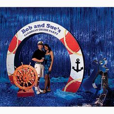 two people are standing in front of an anchor and ship wheel photo booth sign with blue sequins