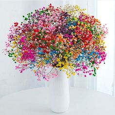 a white vase filled with lots of colorful sprinkles on top of a table