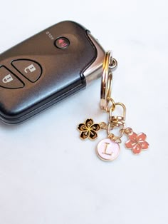 a cell phone is sitting next to a keychain on a white table top