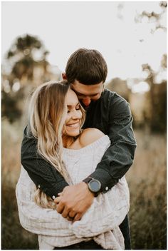 a couple hugging each other in an open field