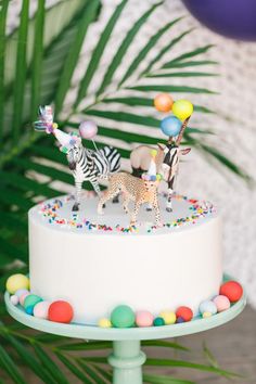 a white cake topped with zebras and balloons