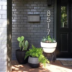 some plants are sitting in front of a door and numbers on the side of a building