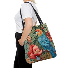 a woman is carrying a colorful parrot tote bag with flowers on the front and side