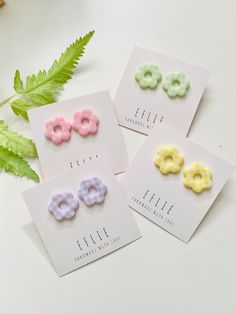 three pairs of colorful hair clips sitting on top of a white table next to a plant